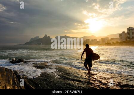 Surfista al tramonto sulla spiaggia di Arpoador a Ipanema a Rio De Janeiro Foto Stock