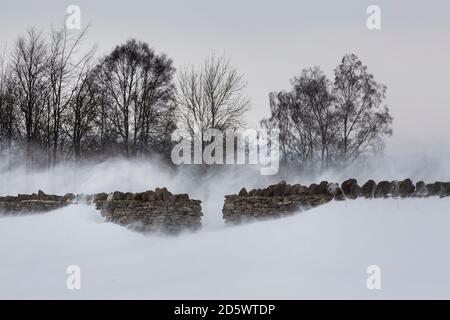 Gap in un muro di pietra in un paesaggio nevoso Foto Stock