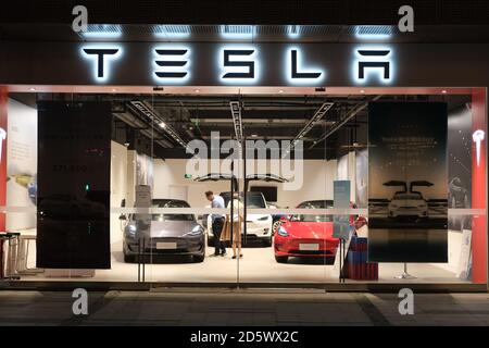 Negozio Facade Tesla di notte. Clienti all'interno del negozio Tesla scelta auto elettriche Foto Stock