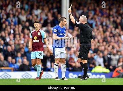 L'arbitro Jonathan Moss (a destra) mostra i Leighton Baines di Everton (a sinistra) il cartellino giallo Foto Stock