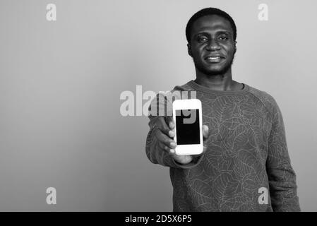 Giovane africano tramite telefono cellulare contro lo sfondo grigio Foto Stock