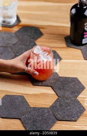 cocktail rosso alcolico in mano su sfondo di legno Foto Stock