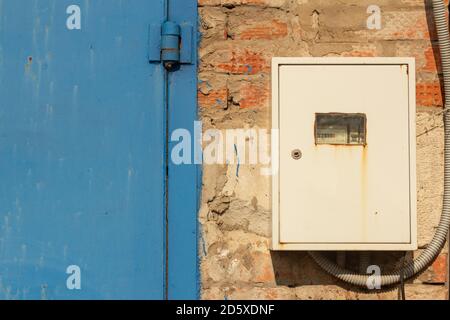 Contatore elettrico chiuso sul vecchio muro di mattoni del garage. Foto Stock
