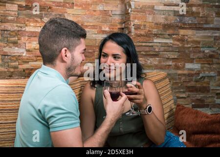 Primo piano ritratto di uomo e donna che tostano vino in una casa rurale. Concetto di coppia interrazziale che ha momenti romantici insieme. Foto Stock