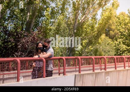 Multi razza coppia in amore abbracciando maschera di indossare viso. Foto Stock