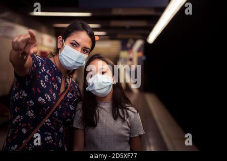 Concetto di trasporto sulla nuova normalità durante l'infezione da coronavirus. Madre e figlia che indossano una maschera chirurgica nel sottosuolo. Foto Stock