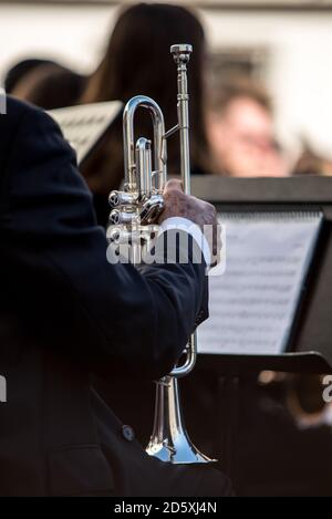 Dettaglio di una classica tromba d'argento in un'orchestra. Foglio di note musicali sullo sfondo fuori fuoco. Foto Stock