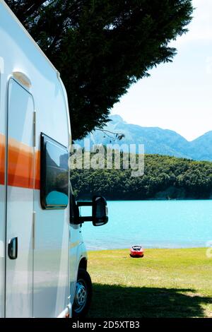 Camper di fronte ad un lago blu con montagne E un Kayak rosso Foto Stock