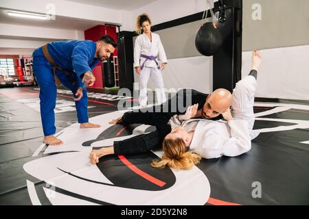 gruppo di quattro partner di arti marziali di judo e un istruttore mettere in pratica nuove tecniche su un tappetino da palestra Foto Stock