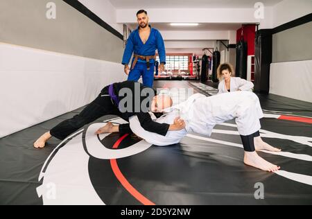 gruppo di quattro partner di arti marziali di judo e un istruttore mettere in pratica nuove tecniche su un tappetino da palestra Foto Stock