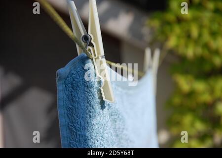 un asciugamano da bagno appeso al filo da una spilla che asciuga al sole sulla terrazza di casa. vita a casa. Foto Stock