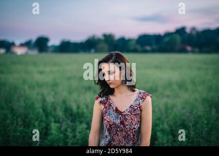 Ritratto di una donna malinconica che indossa un abito in un campo verde Foto Stock