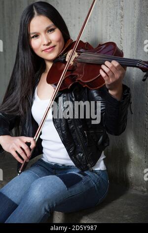 Ritratto di giovane donna violinista Asiatica nella parte anteriore della parete di cemento Foto Stock