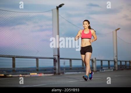 Giovani femmine Asian sportive jogging al crepuscolo Foto Stock