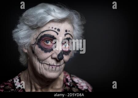 Ritratto di donna senior con teschio di zucchero per il make-up nella parte anteriore del fondo nero Foto Stock