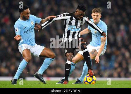 Newcastle United's Christian Atsu (centro) battaglie per la palla con Raheem Sterling di Manchester City (a sinistra) e John Stones di Manchester City Foto Stock