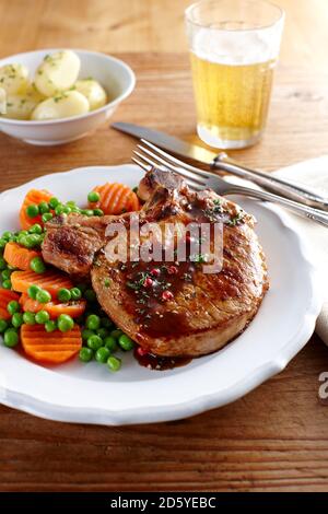 Tritare la carne di maiale con carote, piselli e patate lesse sulla piastra Foto Stock