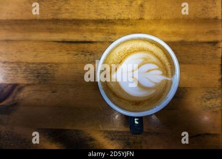 Vista dall'alto del latte di caffè con la forma artistica dei fiori uno sfondo di legno Foto Stock