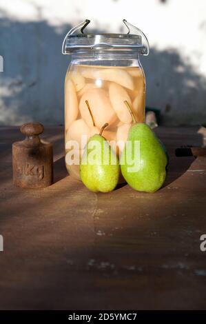 La conservazione di un vasetto di fette di pere, due pere fresche e il vecchio peso Foto Stock