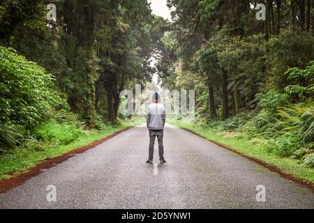 New Zealand, South Island, Jackson Bay, Haast Jackson Bay Road, giovane uomo in piedi sulla strada Foto Stock