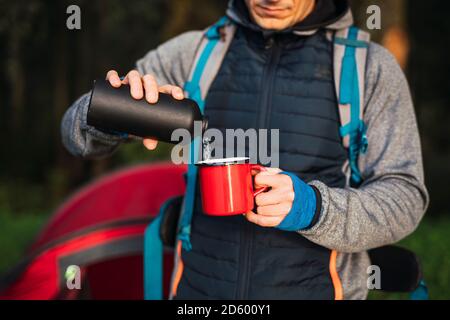 Uomo in campeggio in Estonia, versando acqua in una tazza Foto Stock