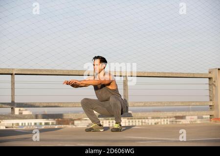 Uomo muscolare facendo squat Foto Stock