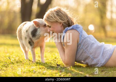 Donna sorridente giacente con piglet in posizione di parcheggio Foto Stock