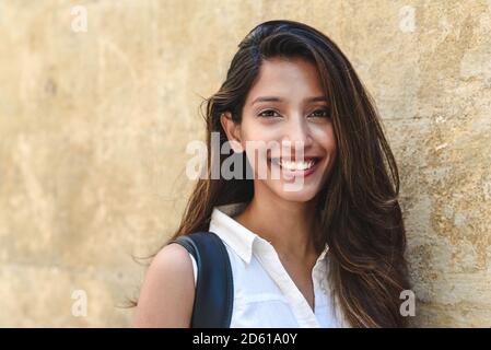 ritratto di una bella donna indiana che guarda a macchina fotografica un sorridendo vicino a un muro di pietra Foto Stock