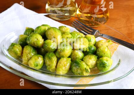 Germogli di Bruxelles arrostiti in un piatto bianco Foto Stock