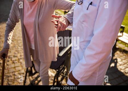 Medico e paziente anziano che vanno di pari passo Foto Stock