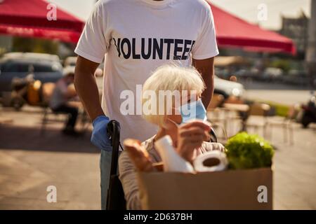 Donna anziana di ritorno volontaria maschile dal supermercato Foto Stock