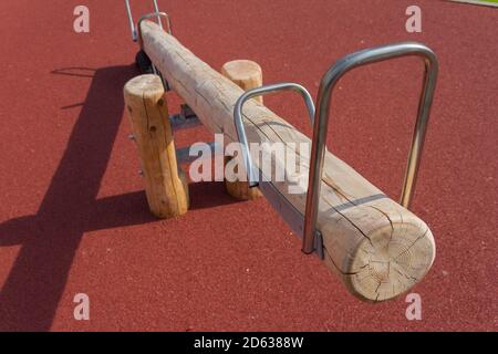 Un'oscillazione fatta di legno sul parco giochi con un superficie sicura in una giornata soleggiata e limpida Foto Stock