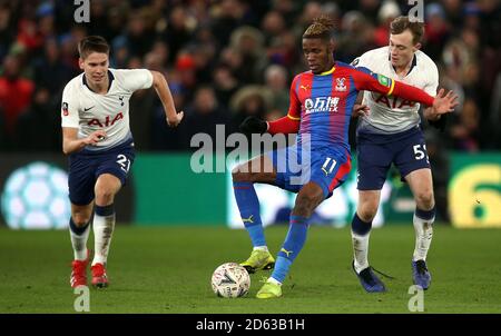 Wilfried Zaha (centro) di Crystal Palace combattimenti per la palla con Juan Foyth di Tottenham Hotspur (a sinistra) e Oliver Skipp Foto Stock