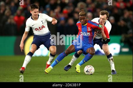 Wilfried Zaha (centro) di Crystal Palace combattimenti per la palla con Juan Foyth di Tottenham Hotspur (a sinistra) e Oliver Skipp Foto Stock