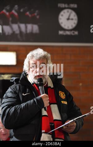 Pete Martin canta i Fiori di Manchester come tifosi di calcio Ascolta un servizio memoriale per commemorare l'aereo di Monaco Crash sotto l'orologio di Monaco fuori Old Trafford Foto Stock