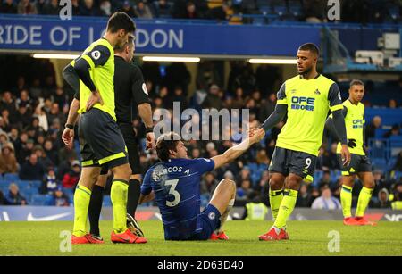 Il Marcos Alonso di Chelsea (centro) è aiutato fuori terra da Elias Kachunga di Huddersfield Town (a destra) Foto Stock