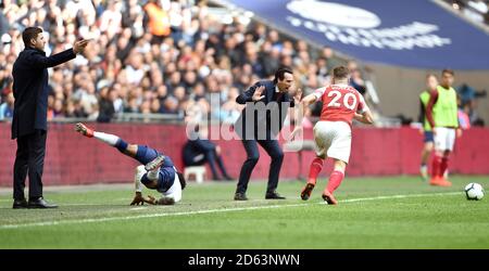 Tottenham Hotspur's Danny Rose (seconda a sinistra) Va a terra dopo una sfida da Shkodran Mustafi dell'Arsenal (A destra) come il manager Arsenale Unai Emery (al centro) guarda su e. Tottenham Hotspur manager Mauricio Pochettino (a sinistra) Foto Stock