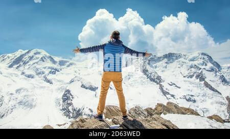 Zermatt, Svizzera - Maggio 2017: L'uomo in cima alla montagna si affaccia sul paesaggio innevato di montagna con vittoria e gioia Foto Stock
