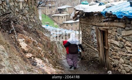 Bitlis, Turchia - Marzo 2020: Donna turca in abiti tradizionali camminando in una piccola strada del villaggio Foto Stock