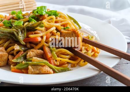 Mangiare pollo giapponese yakisoba tagliatelle con bacchette Foto Stock