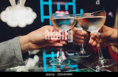 Primo piano di un gruppo di persone che graffia bicchieri con vino o champagne davanti allo sfondo bokeh. Mani di persone anziane. Foto Stock