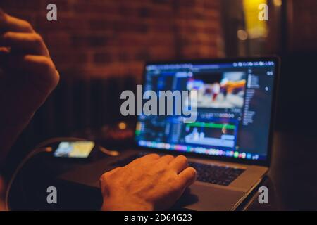 La mano del DJ sul computer portatile e la console di mixaggio che controlla le impostazioni audio. Foto Stock