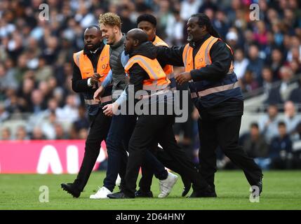 Un invasore di pitch è assortito fuori dal pitch da stewards Foto Stock