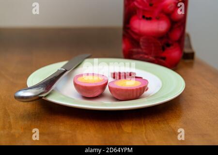 Sliced organic pickled beet eggs on wooden table Stock Photo