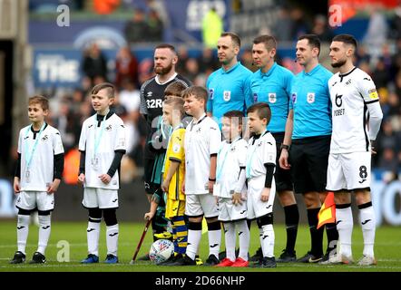 Derby County Captain Wayne Rooney (a sinistra) e Swansea City Captain Matt Grimes posa per una foto con i quattro ufficiali e le mascotte prima dell'inizio della partita Foto Stock