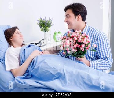 La cura amorevole marito visitando moglie incinta in ospedale Foto Stock