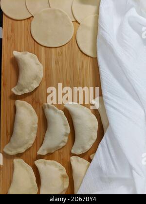 Pierogis e pasta su tavola di legno, parzialmente ricoperta di tela di cotone bianca Foto Stock