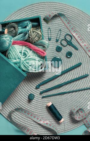 aghi a crochet per palle da maglieria di fili di lana e nastro misurare su un tavolo con texture verde in vista dall'alto Foto Stock