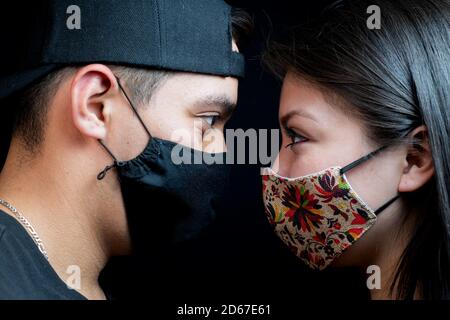Primo piano ritratto di una giovane coppia amorevole che guarda ciascuno altro mentre si indossa una maschera protettiva per il viso Foto Stock