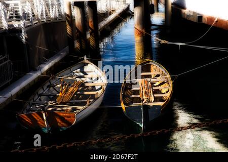 Guardando verso il basso su due canoe con pale che si posano all'interno ormeggiato tra due bacini in un ambiente industriale Foto Stock